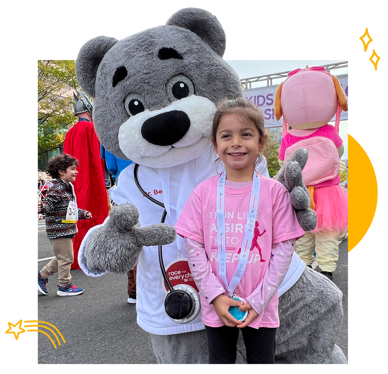 A young girl wearing a pink Girls on the Run shirt and medal smiles while standing next to a person in a large gray bear mascot costume at the Race for Every Child outdoor event. Other costumed characters appear in the background.
